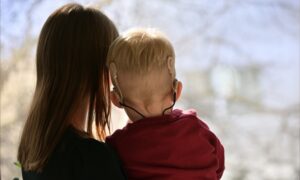 Back of a mother carrying her child in her arms watching the view