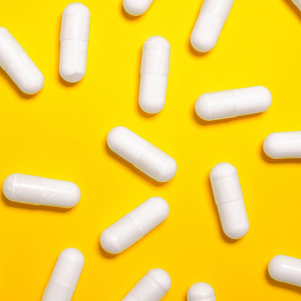 White capsuled medicine tablets against yellow background