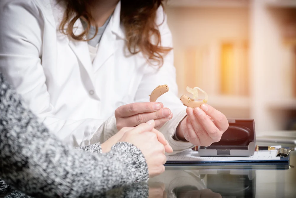 Hearing care professional holding hearing aids and speaking to patient