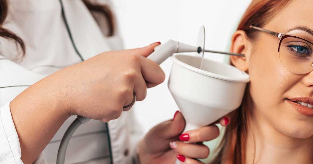 An audiologist doing ear syringing for a young lady patient.
