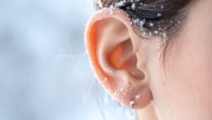 A ear covered in snowflakes, showcasing winter hearing problems.